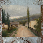 Painting of a village scene with a dirt road, framed by decorative lace