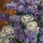 Close-up of purple and white flowers in a vase on a wooden surface